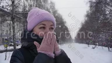 街上一位年轻女子的肖像，她在冬天的公园里散步时，双臂呼吸以保暖。 慢慢